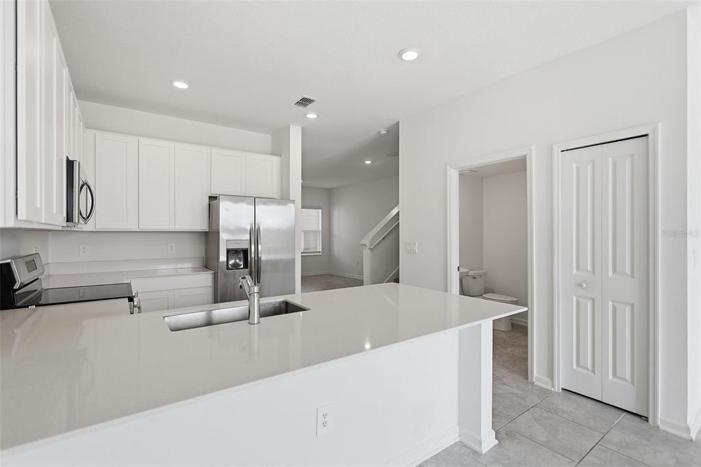 3303 Laurent Loop Davenport, FL 33837 - Photo 9 of 37 a kitchen with stainless steel appliances a sink a stove a refrigerator and cabinets