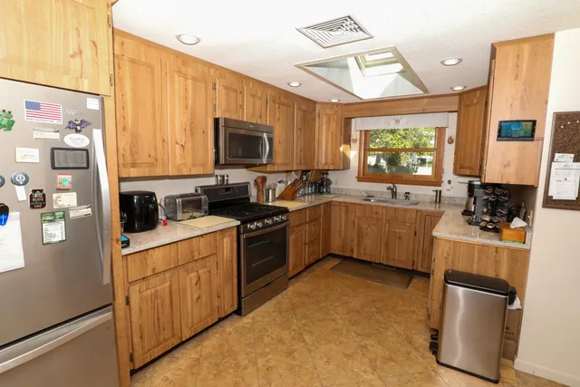 a kitchen with stainless steel appliances a stove a sink a refrigerator a window