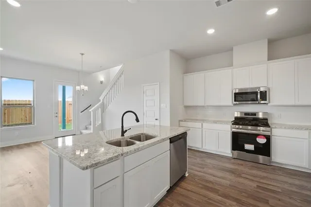 a kitchen with stainless steel appliances a sink a stove a refrigerator cabinets and a dining table