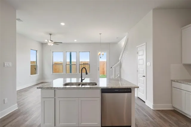 a kitchen with granite countertop white cabinets and wooden floor