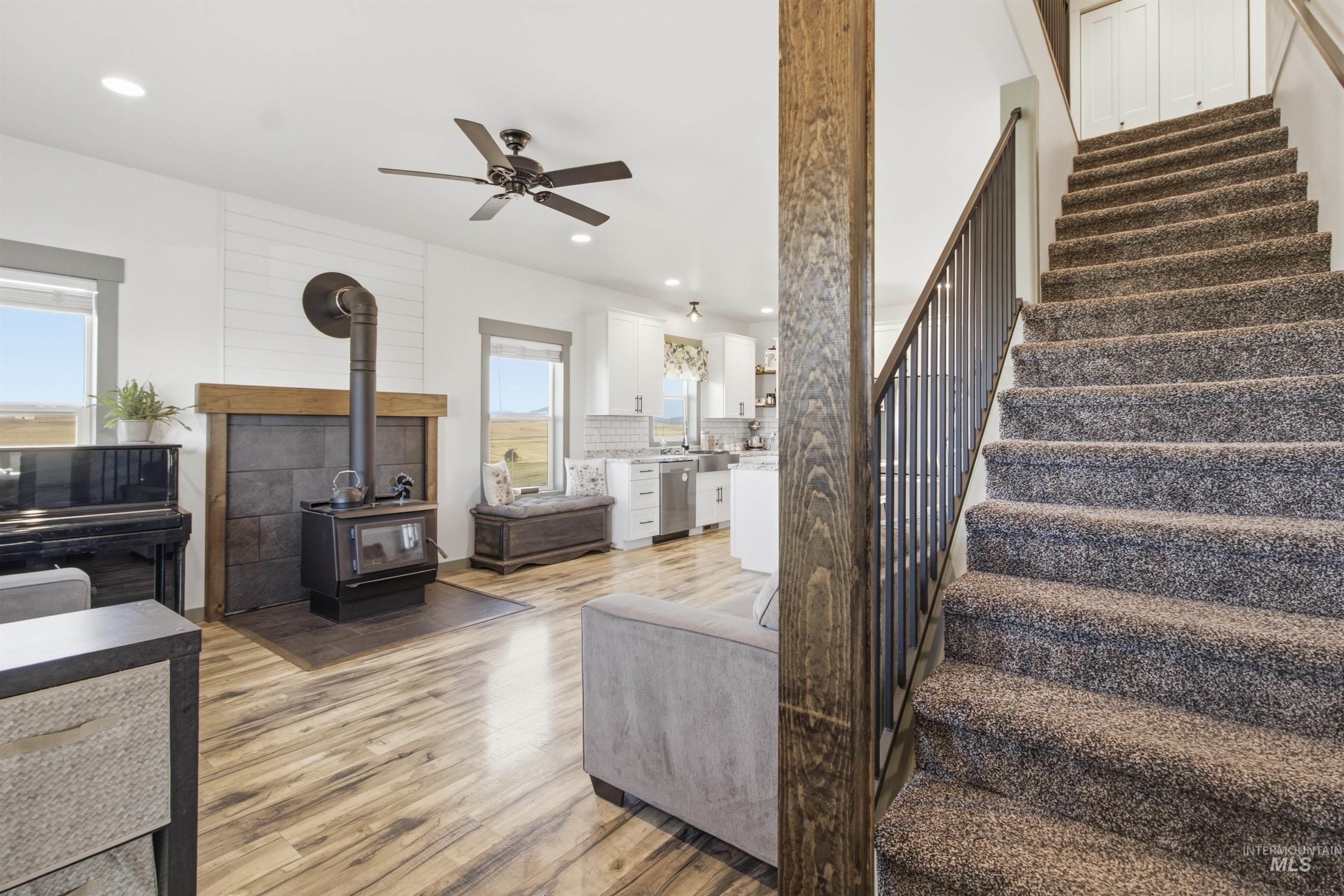 1032 Duffield Flat Road Potlatch, ID 83855 - Photo 26 of 50 Open-concept living area with wood-finish flooring, a wood-burning stove with a stone surround, and a ceiling fan