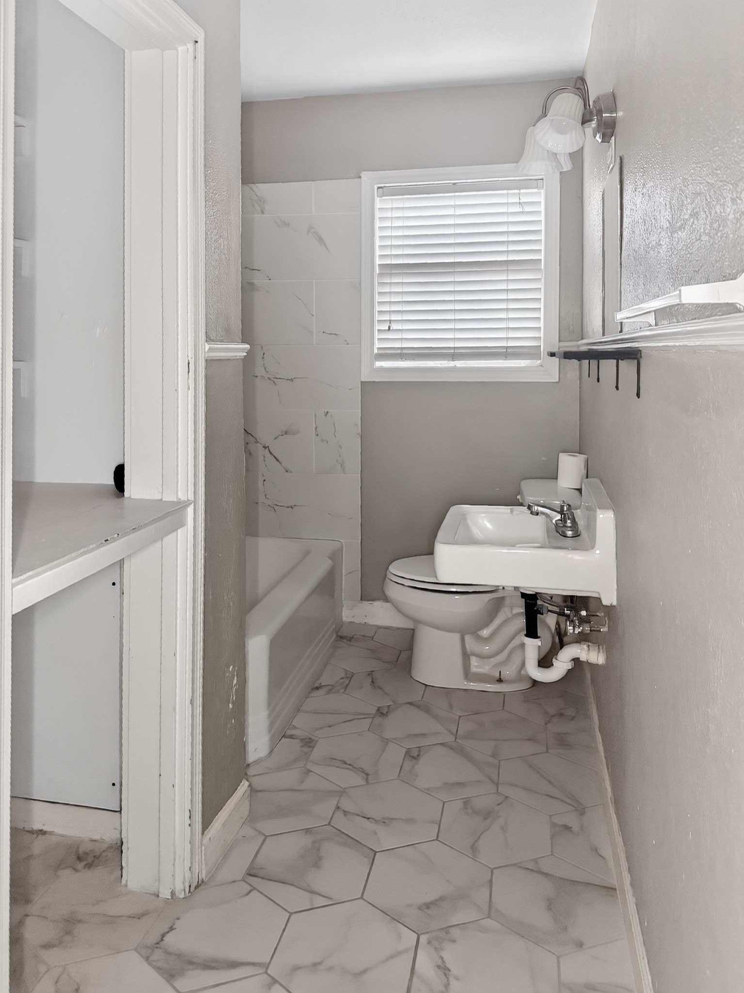 2313 Avenue L Rosenberg, TX 77471 - Photo 21 of 31 Renovated bathroom with marble-look flooring, updated fixtures, and a bright window providing natural light.