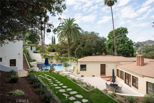 a view of a white house with a big yard and potted plants