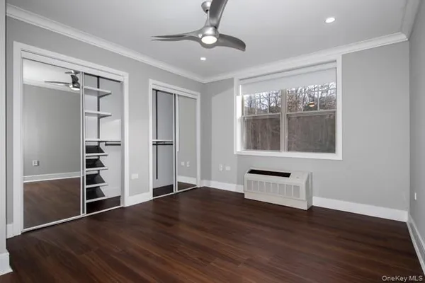 a view of an empty room with a window and wooden floor