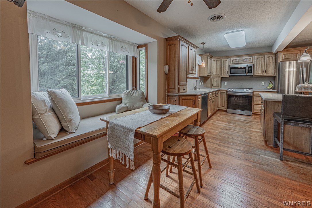 6775 Bear Ridge Road Pendleton, NY 14094 - Photo 9 of 48 Warm wood flooring and classic wooden cabinetry define this inviting kitchen and adjacent dining area.