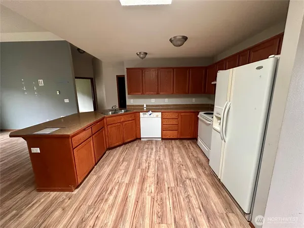 a kitchen with stainless steel appliances granite countertop a refrigerator a sink dishwasher a stove and white countertops with wooden floor
