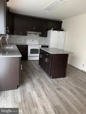 a kitchen with stainless steel appliances granite countertop a sink a stove a refrigerator and cabinets