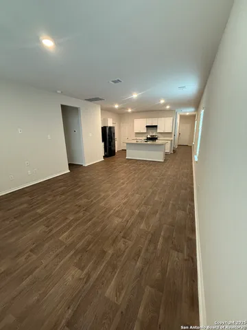 a large room with kitchen island a sink wooden floor and a view of living room