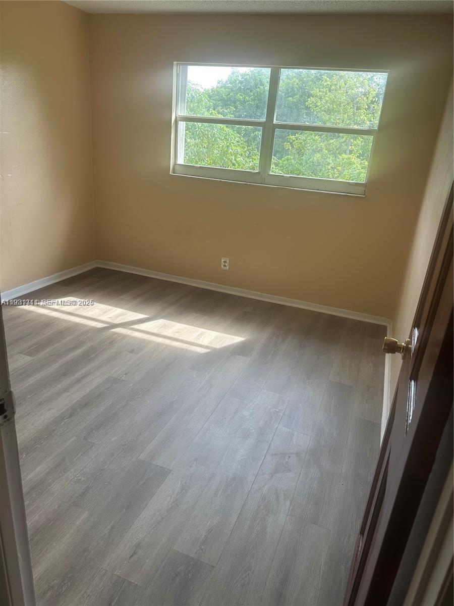 948 Southwest 74th Avenue North Lauderdale, FL 33068 - Photo 7 of 10 an empty room with wooden floor and windows