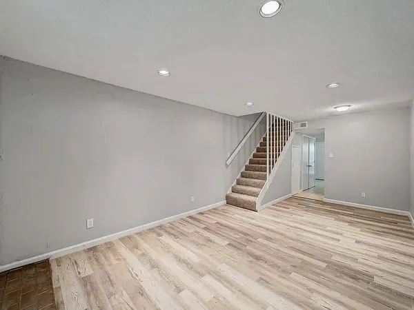 a view of an empty room with wooden floor and stairs