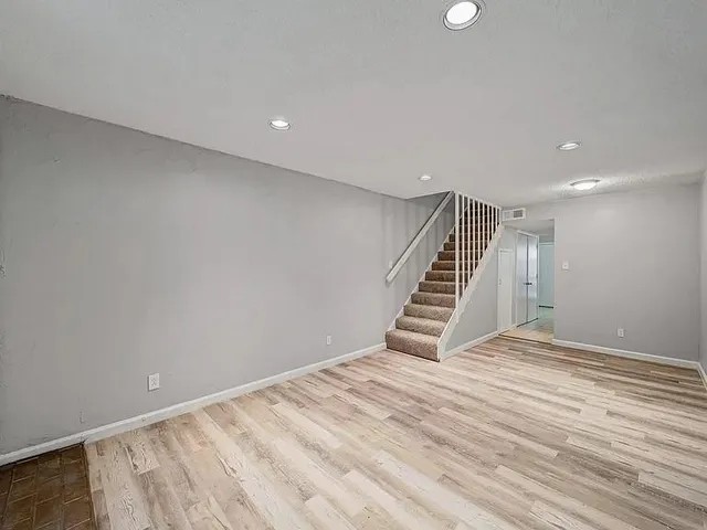 a view of an empty room with wooden floor and stairs