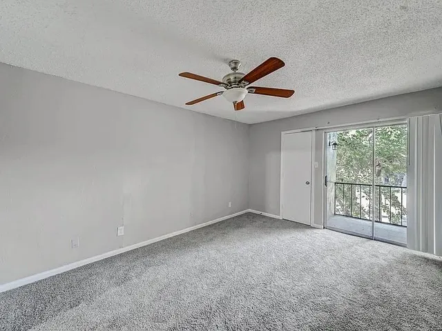 an empty room with windows and ceiling fan