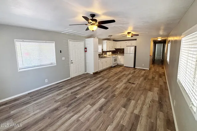 a view of empty room with wooden floor and fan