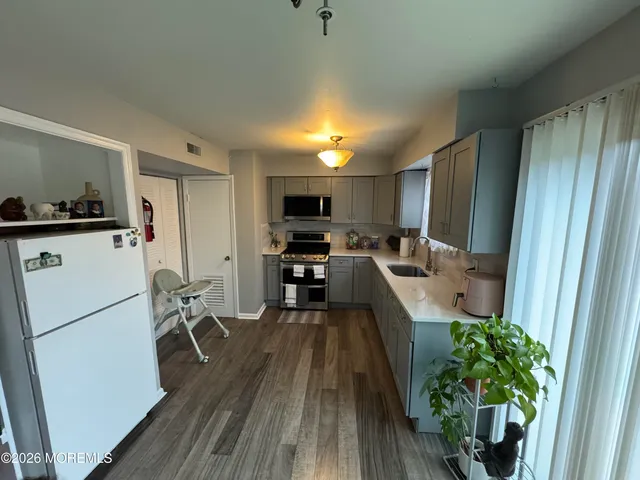 a kitchen with sink a refrigerator and wooden floor