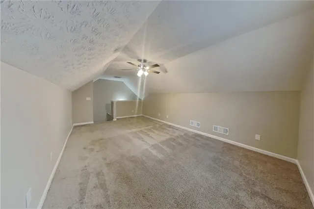 an empty room with a chandelier fan and windows