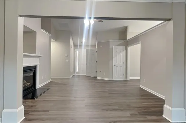 a view of an empty room with wooden floor and a fireplace
