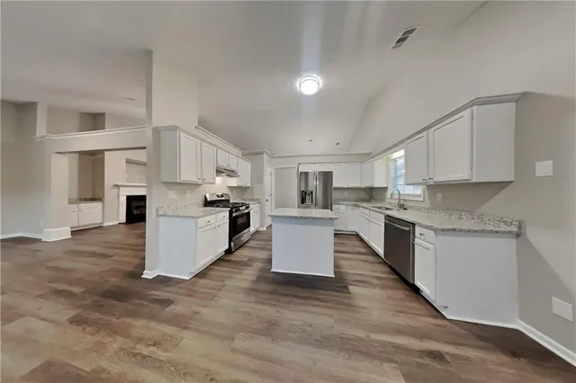 a large kitchen with cabinets wooden floor and stainless steel appliances