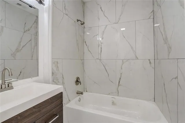 an empty room with wooden floor chandelier fan and windows