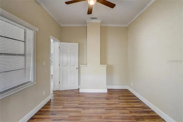 a view of an empty room with wooden floor and a window
