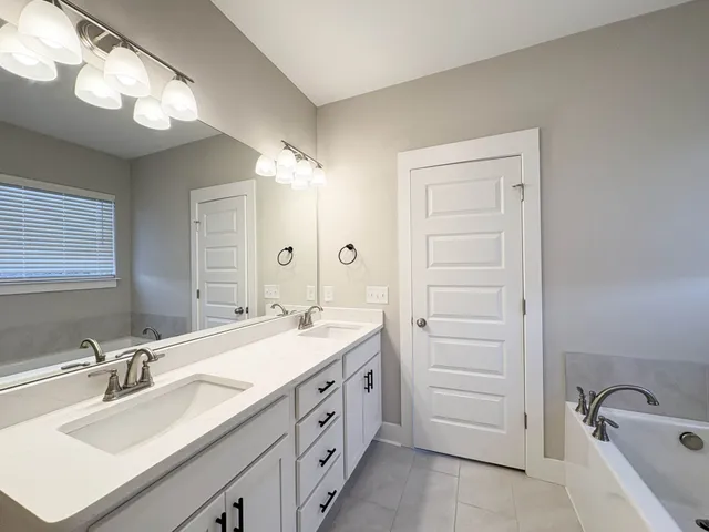 a spacious bathroom with a double vanity sink mirror and bathtub