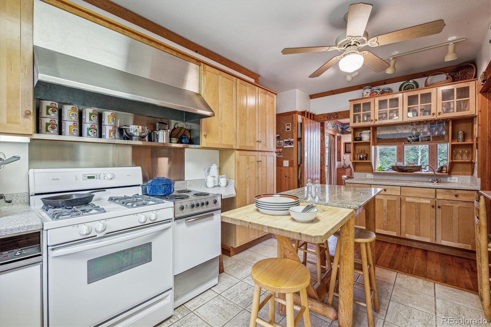 12973 Upper Ridge Road Conifer, CO 80433 - Photo 11 of 46 a open kitchen with stainless steel appliances granite countertop a stove a chimney a dining table and chairs with wooden floor