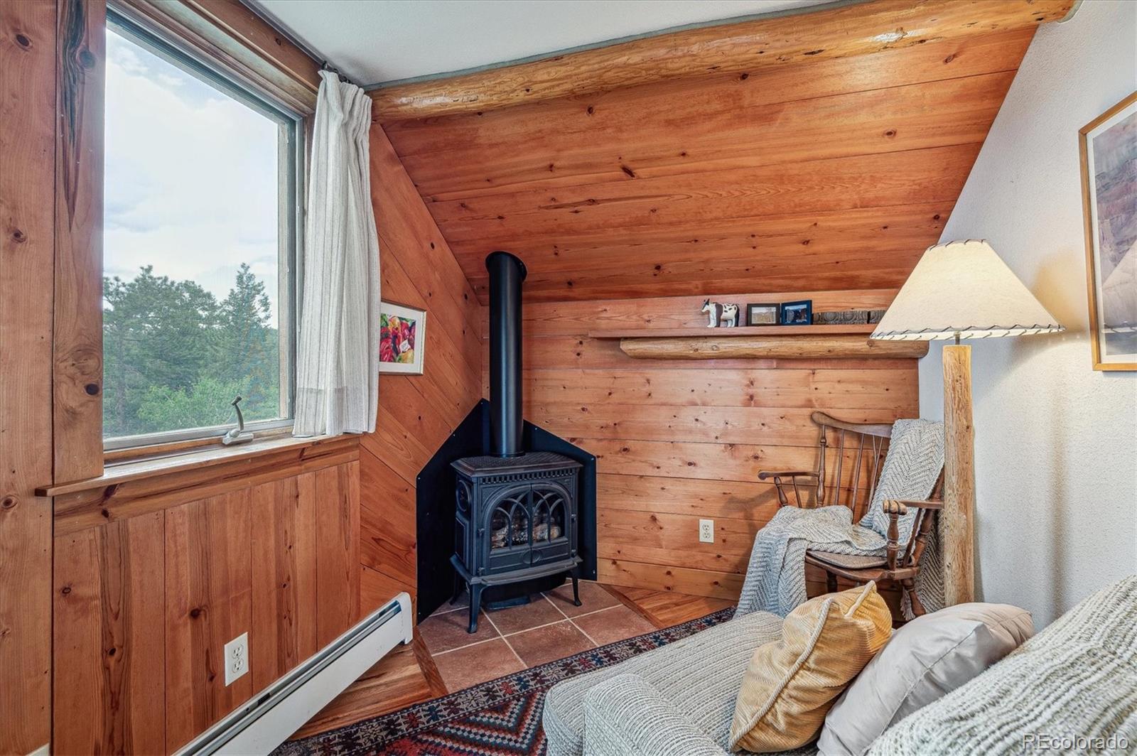 12973 Upper Ridge Road Conifer, CO 80433 - Photo 18 of 46 a bedroom with a bed and a fireplace