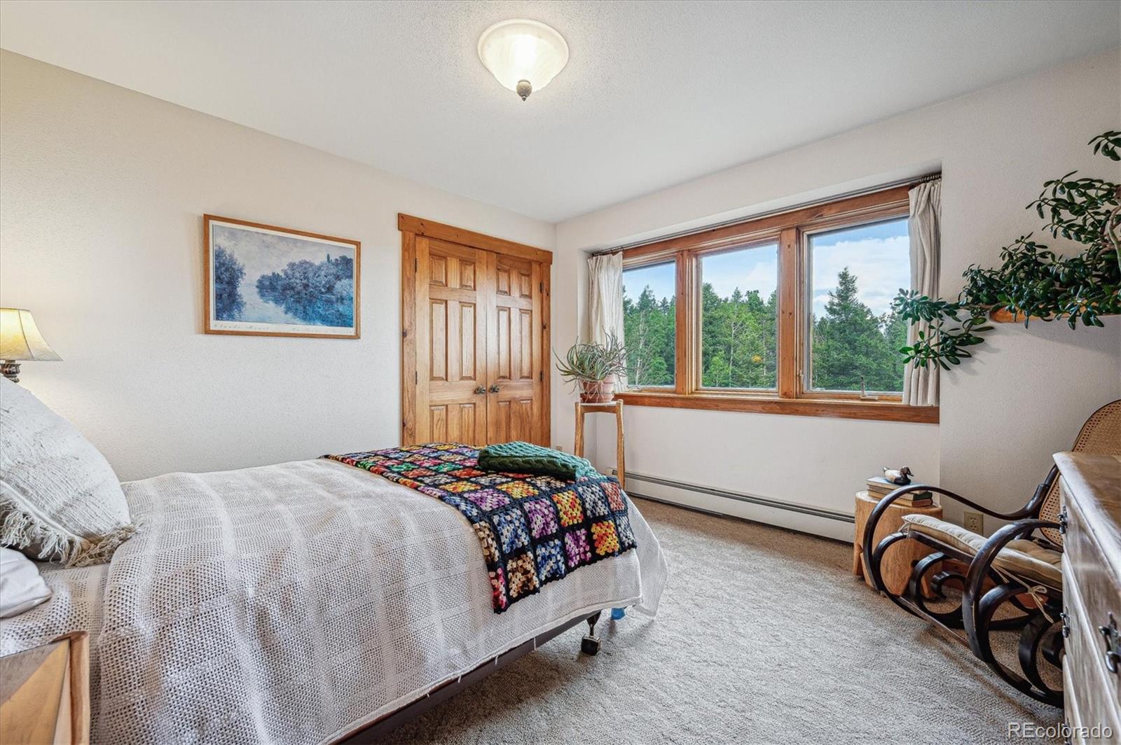 12973 Upper Ridge Road Conifer, CO 80433 - Photo 20 of 46 a bedroom with a bed a couch and a window
