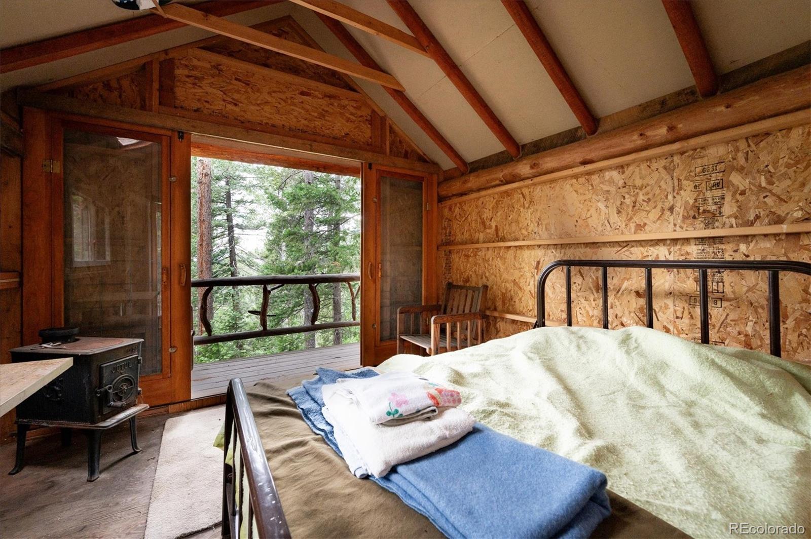 12973 Upper Ridge Road Conifer, CO 80433 - Photo 36 of 46 a bedroom with furniture and a window