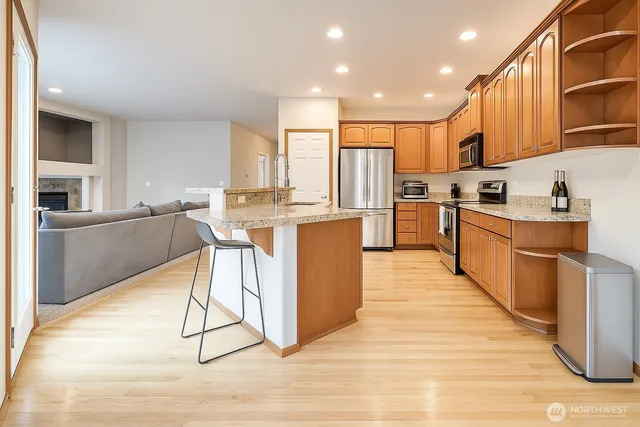 a kitchen with granite countertop a stove top oven a sink dishwasher a dining table and chairs with wooden floor