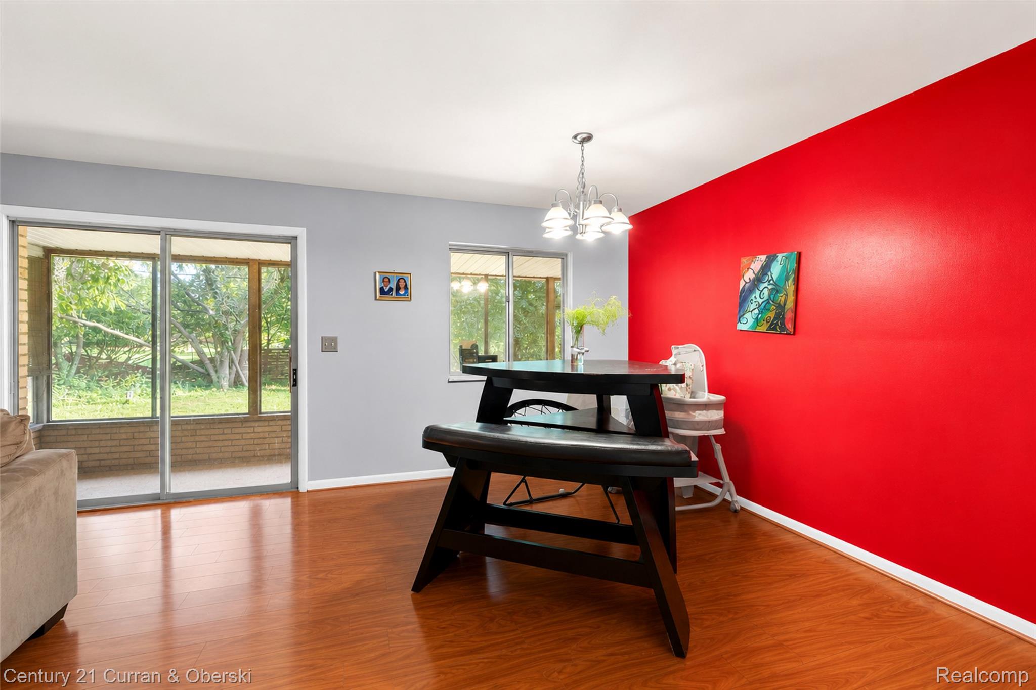 4652 Patrick Road West Bloomfield, MI 48322 - Photo 10 of 27 Bright interior space featuring wood-finish flooring, a contemporary chandelier, and a vibrant red accent wall