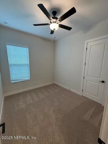 an empty room with a ceiling fan and window