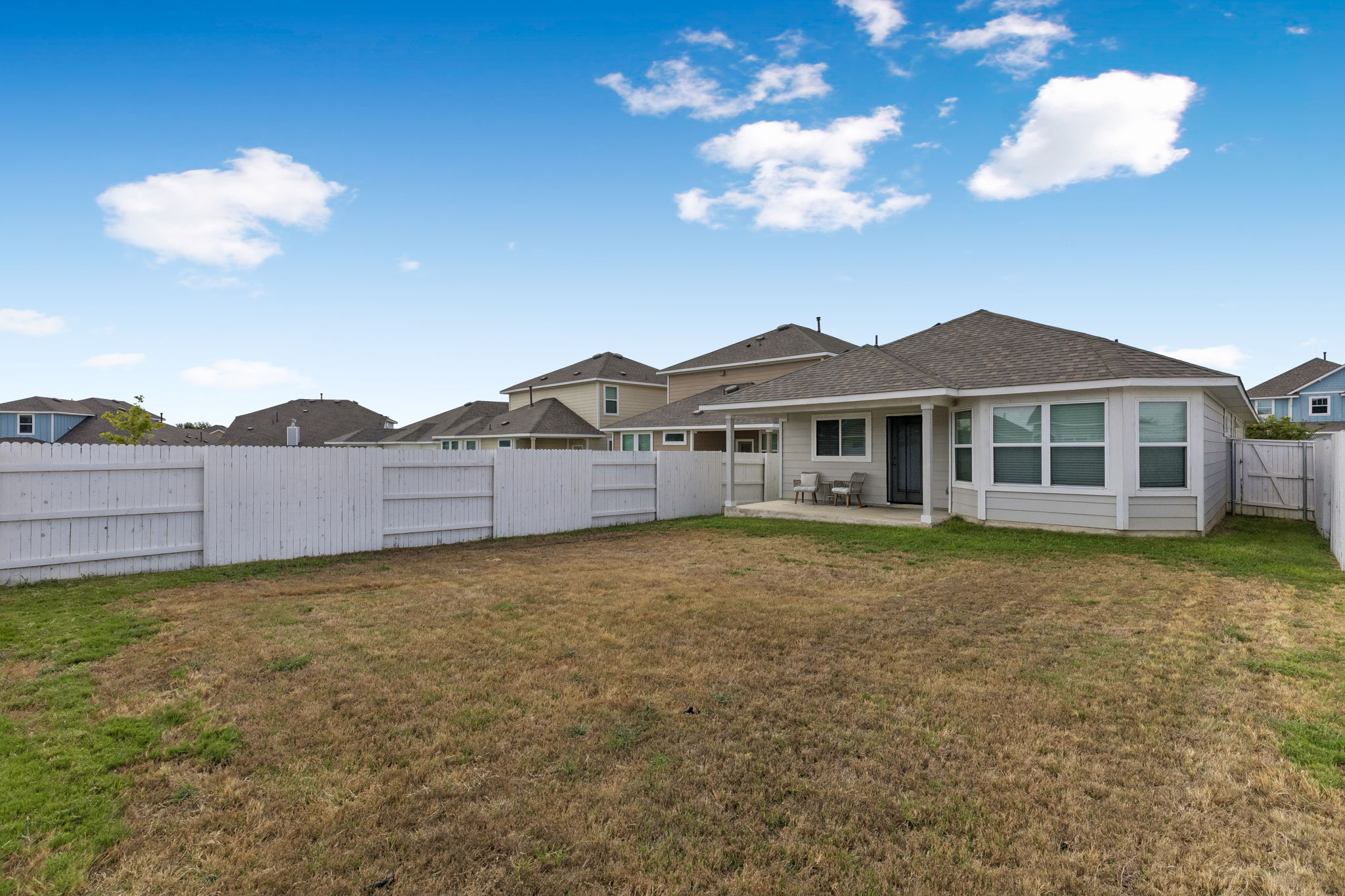164 Appleberry Lane Elgin, TX 78621 - Photo 25 of 40 A spacious, fully fenced yard features a covered back porch looking out over the lawn.