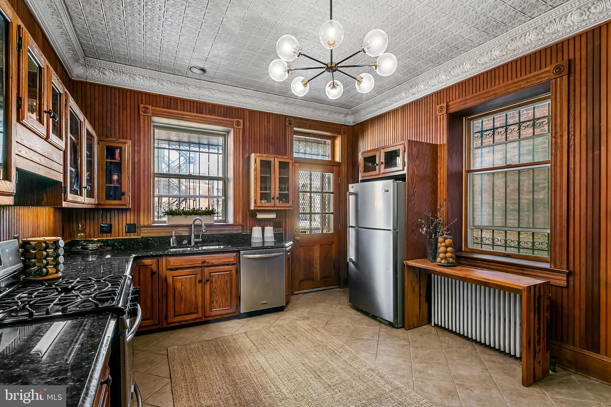 2243 Eutaw Place Baltimore, MD 21217 - Photo 29 of 54 a kitchen with stainless steel appliances granite countertop a refrigerator a stove a sink dishwasher a dining table and chairs with wooden floor
