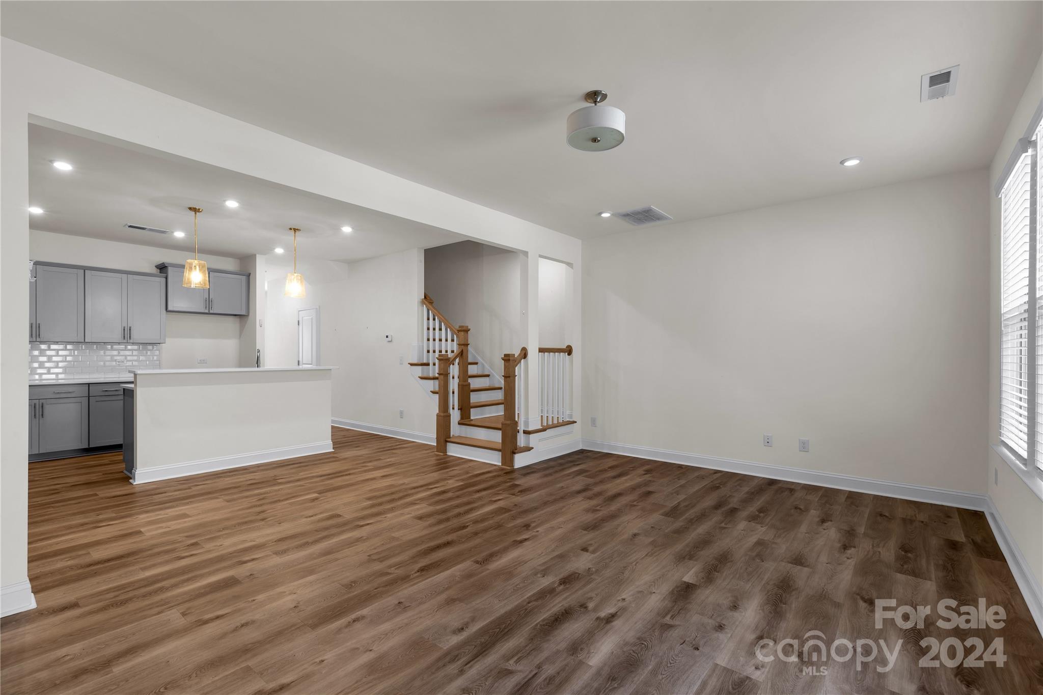 2026 Sutton View Road, Unit 693 Fort Mill, SC 29708 - Photo 9 of 26 an empty room with wooden floor and a kitchen