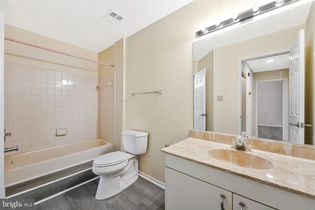 a bathroom with a granite countertop sink a toilet and shower