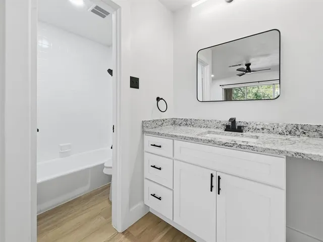 a bathroom with a granite countertop sink a mirror and a bathtub