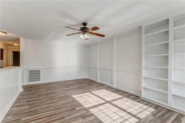 a view of empty room with wooden floor and fan