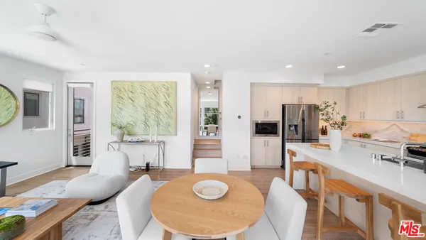 a living room with stainless steel appliances granite countertop furniture and a wooden floor