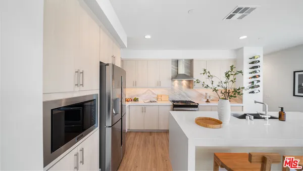 a very nice looking living room with stainless steel appliances furniture a refrigerator and a kitchen view