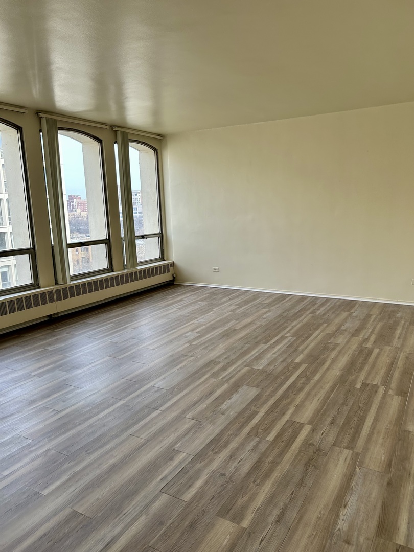 1450 East 55th Place, Unit 825S Chicago, IL 60637 - Photo 5 of 15 a view of an empty room with wooden floor and a window