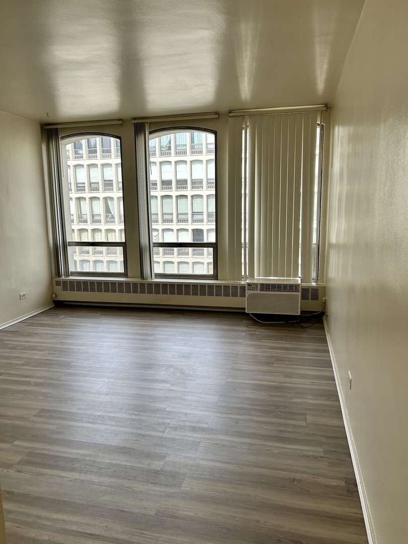 1450 East 55th Place, Unit 825S Chicago, IL 60637 - Photo 8 of 15 wooden floor with window in an empty room