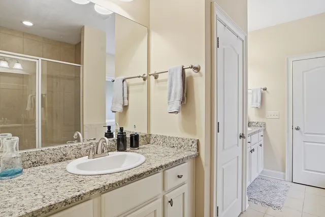 a bathroom with a granite countertop sink a mirror and a shower