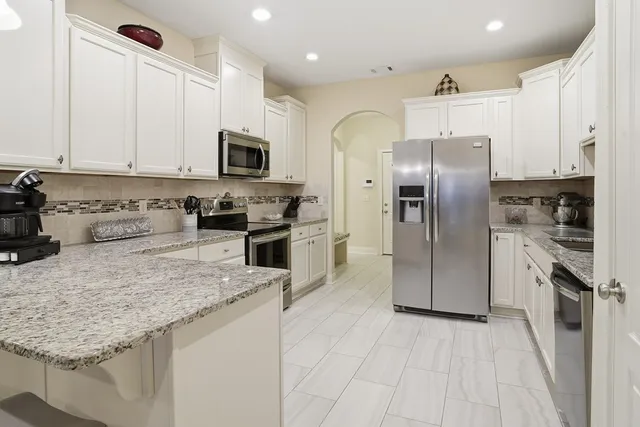 a kitchen with stainless steel appliances granite countertop a refrigerator a stove and a sink