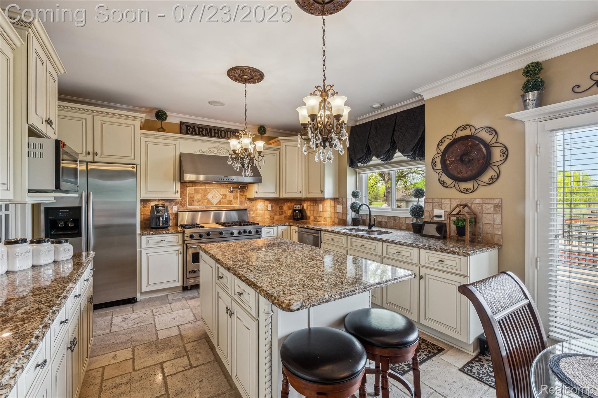 5460 Cochrane Road Almont, MI 48003 - Photo 10 of 48 Gourmet kitchen featuring a central island with granite countertop, stainless steel appliances, white cabinetry with crown molding, natural stone tile backsplash, and elegant chandelier lighting