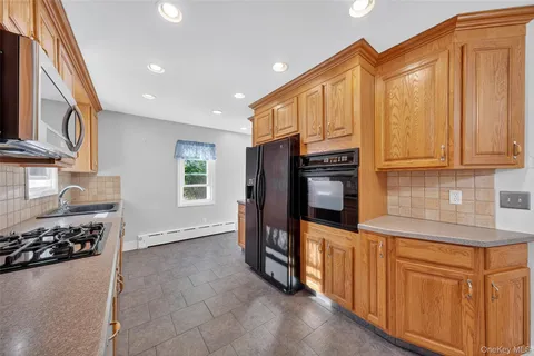 a kitchen with stainless steel appliances granite countertop a refrigerator a stove and a sink with wooden cabinets