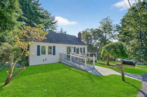 a view of house with a big yard and large trees