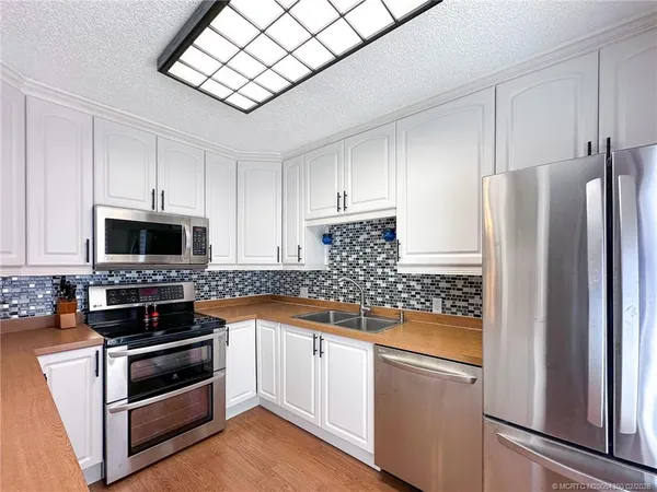 a kitchen with stainless steel appliances white cabinets and a stove top oven