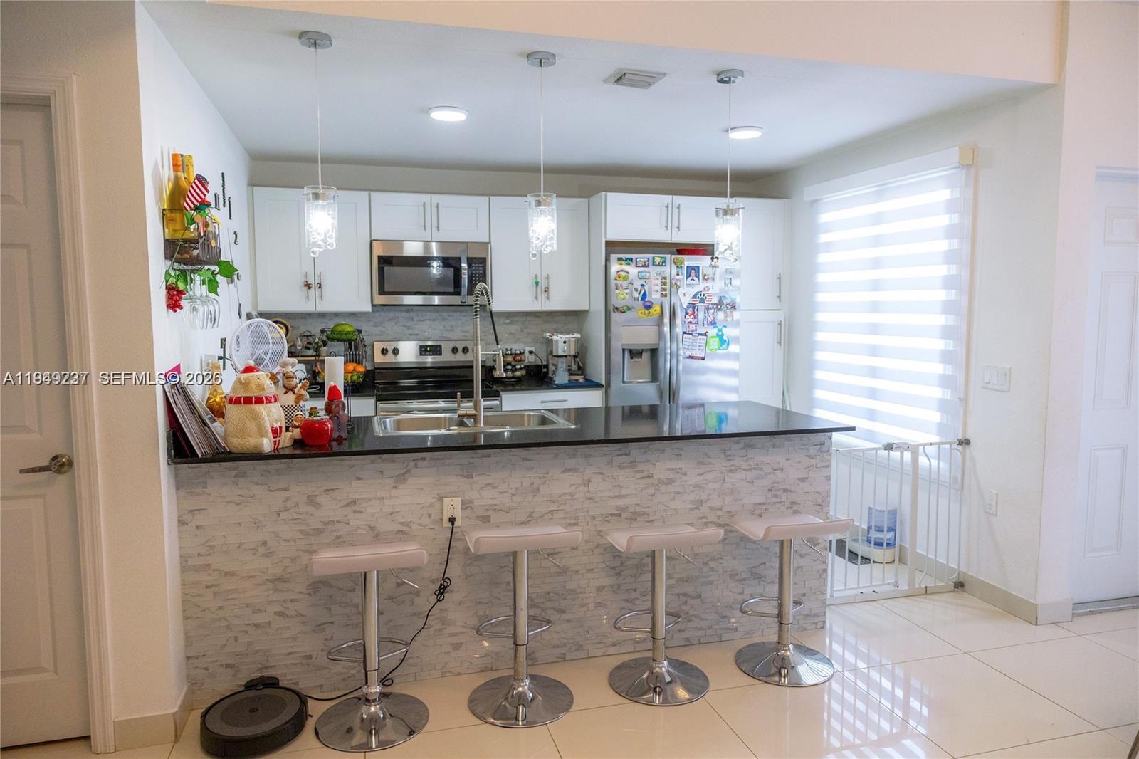 25874 Southwest 139th Path, Unit 25874 Homestead, FL 33032 - Photo 2 of 7 a kitchen with stainless steel appliances kitchen island granite countertop a sink and a refrigerator