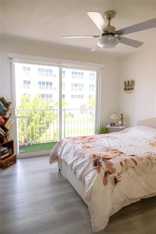 a bedroom with a bed and a large window with wooden floor