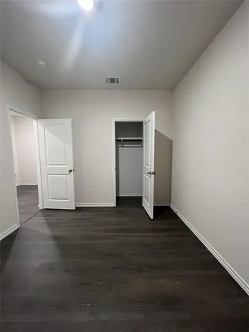 a view of an empty room with wooden floor and closet